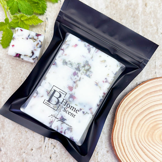 Botanical Blackberry Frost & Cedarwood Wax Melt Bar with Dried Petals in Black Resealable Packaging, Styled with Green Leaves and Wooden Slice