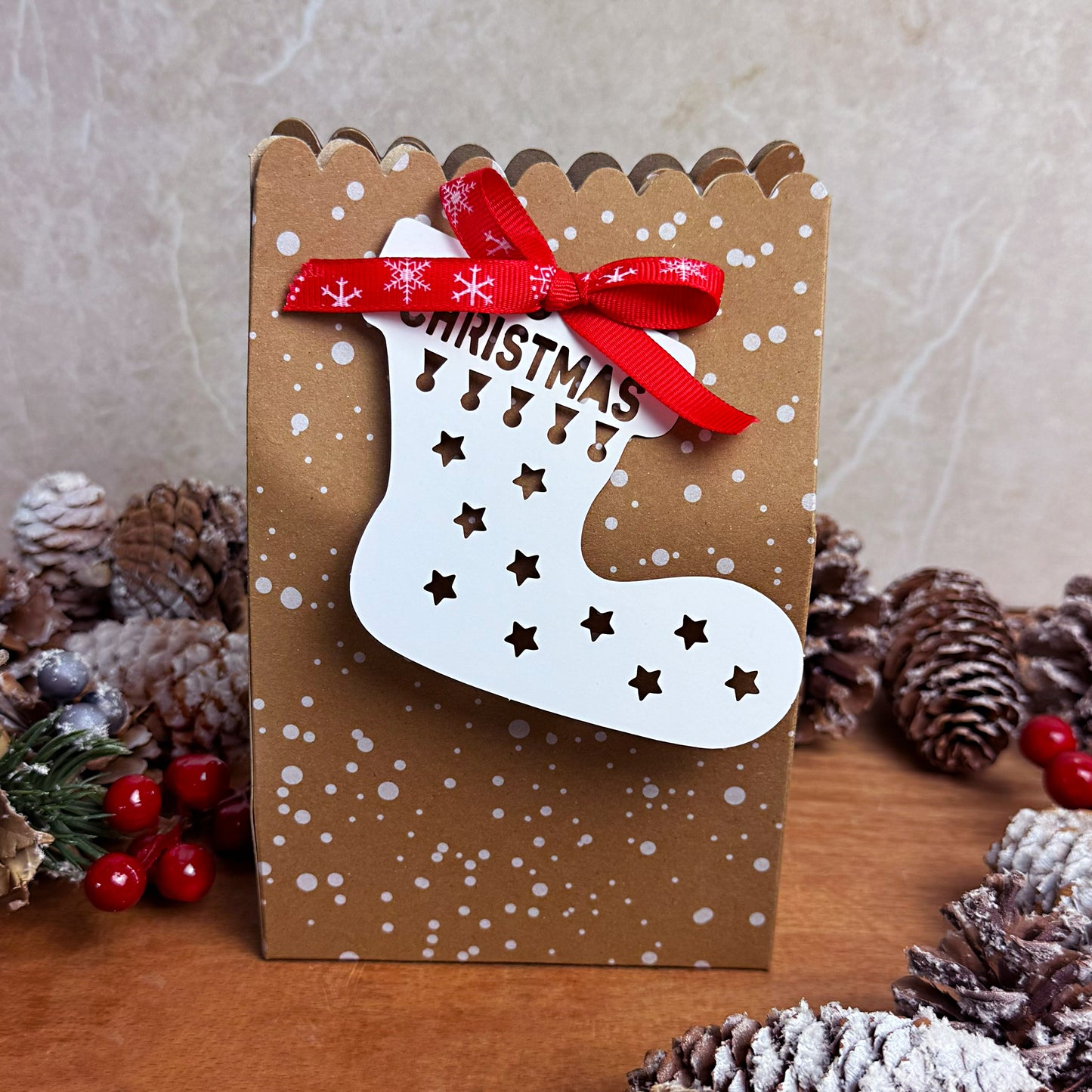 Wax Melt Advent calendar white Christmas stocking design and red ribbon on a wooden surface with pine cones and berries.
