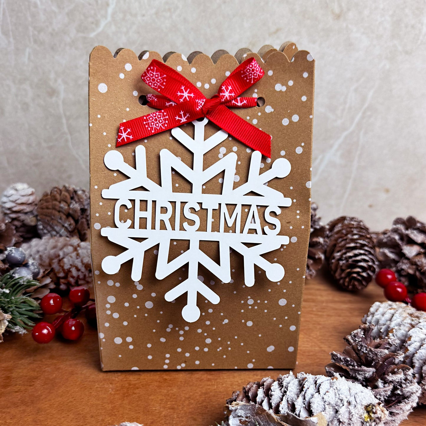 Wax Melt Advent calendar with a red ribbon and snowflake design on a wooden surface with pine cones and berries.
