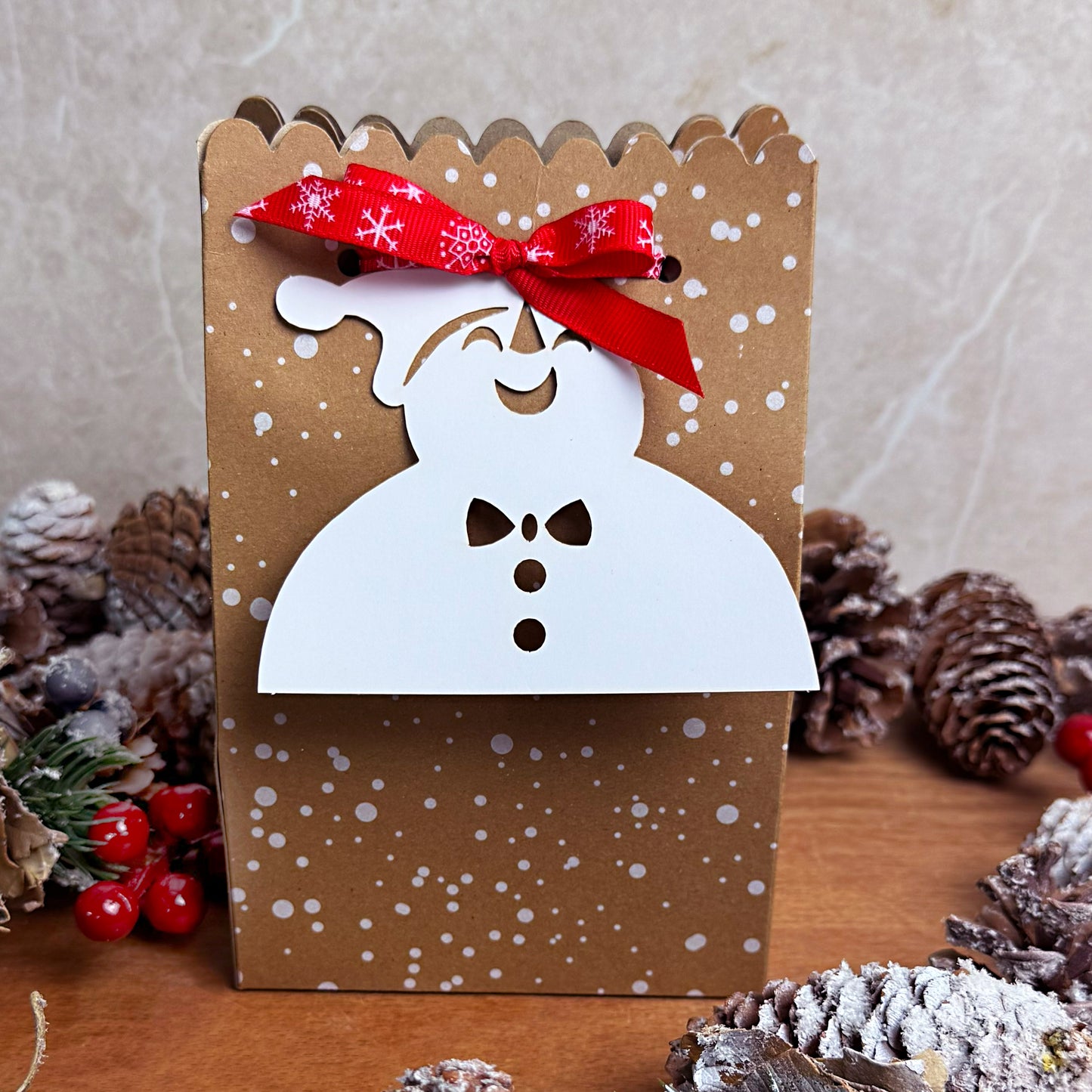 Wax Melt Advent calendar with a snowman design and red bow, surrounded by pine cones and berries.