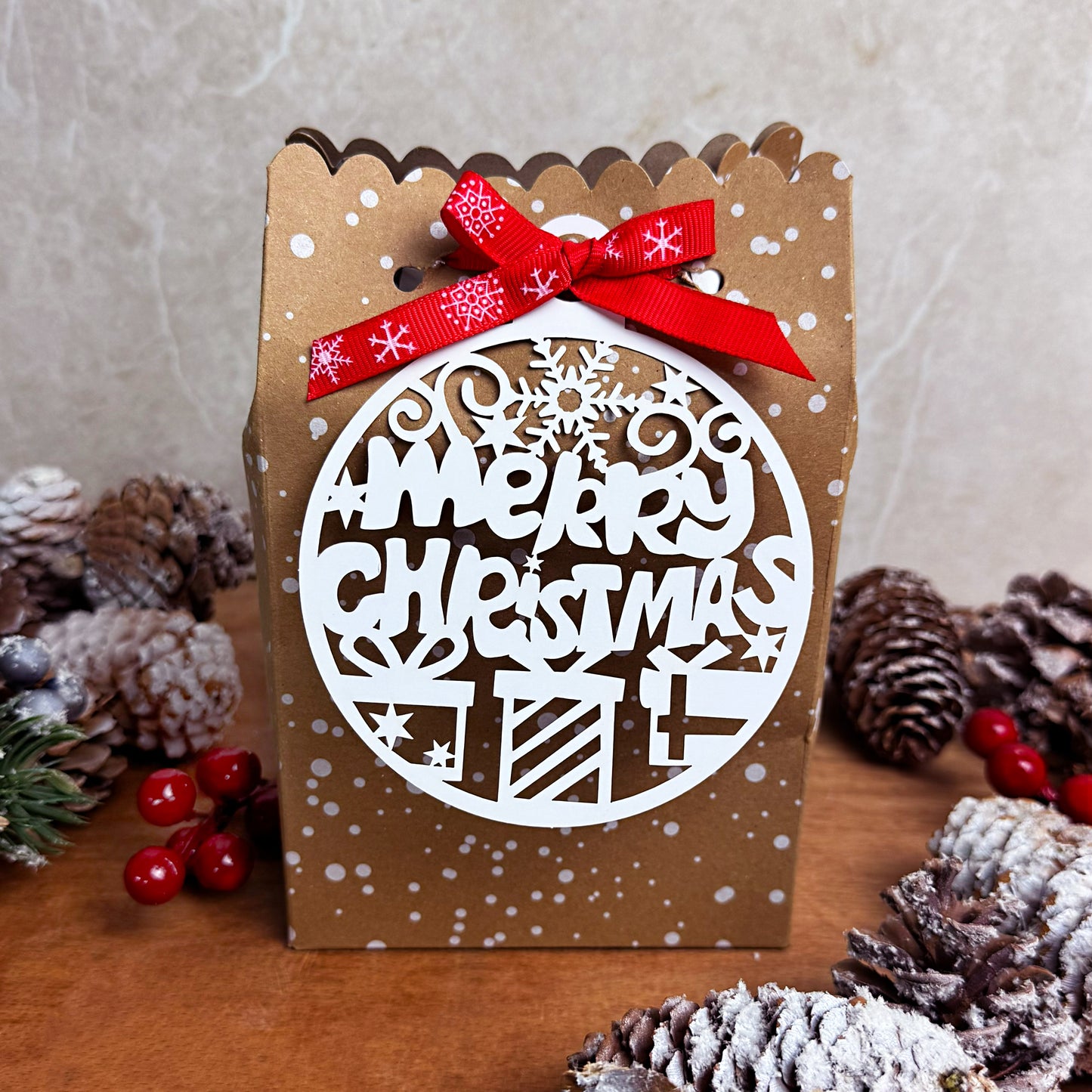 Wax melt advent calendar with 'Merry Christmas' design and red ribbon, surrounded by pine cones and berries on a wooden surface.