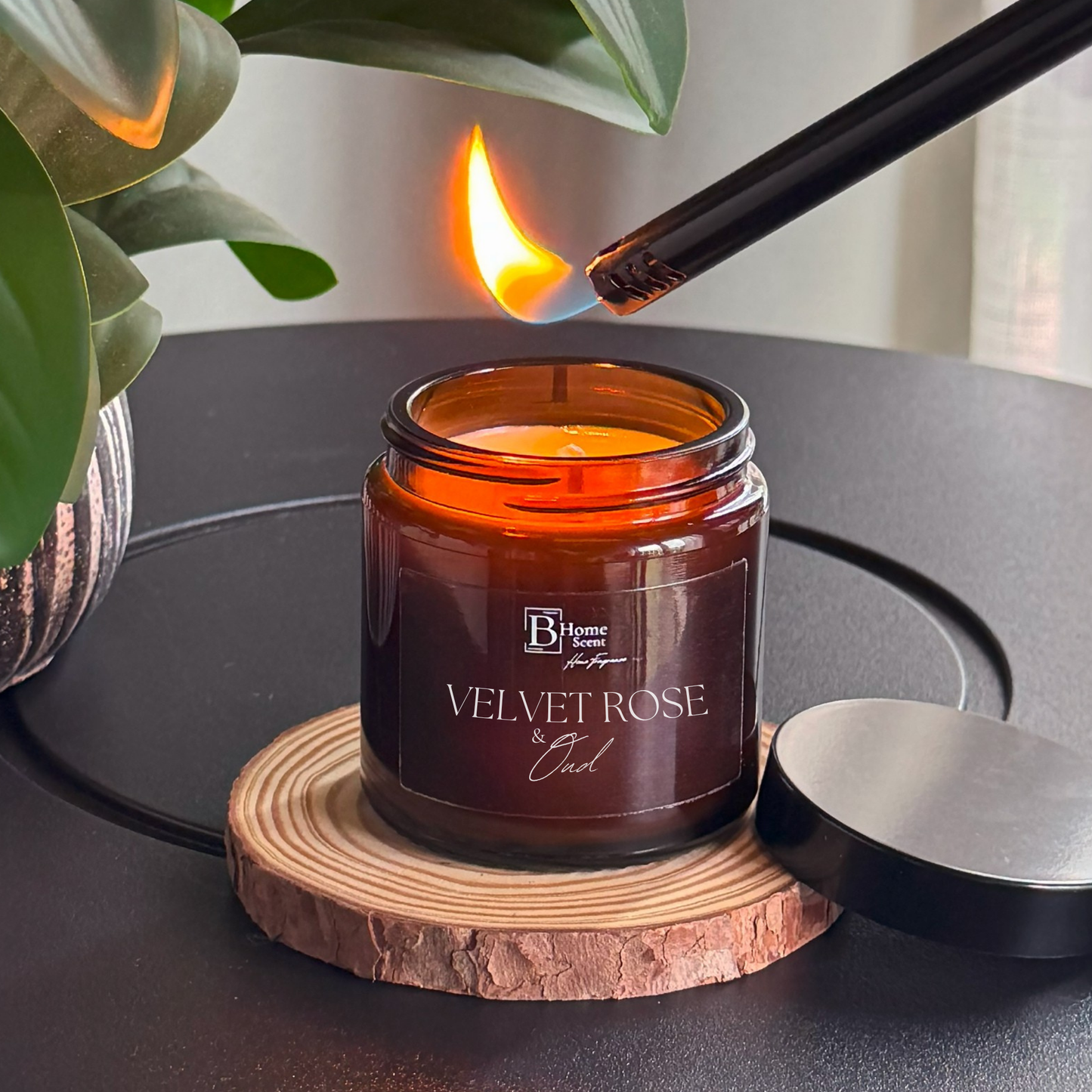 Amber jar velvet rose and oud scented candle lit on a wooden surface