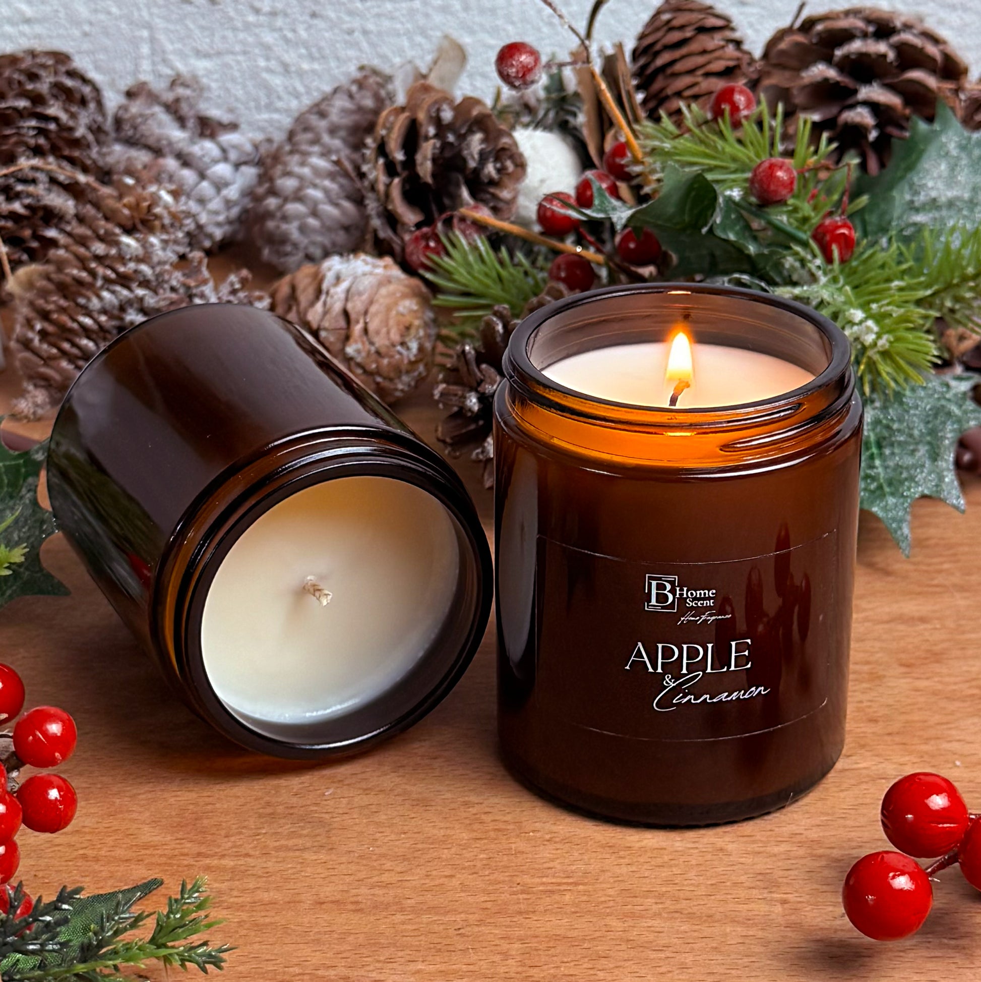Lit Apple and Cinnamon Christmas candle in an amber glass jar surrounded by pinecones and holiday décor.

Option 3 (Product-Focused):