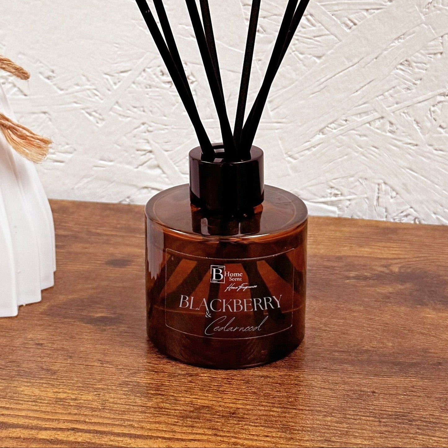 Blackberry and Cedarwood reed diffuser in amber glass bottle styled on wooden table