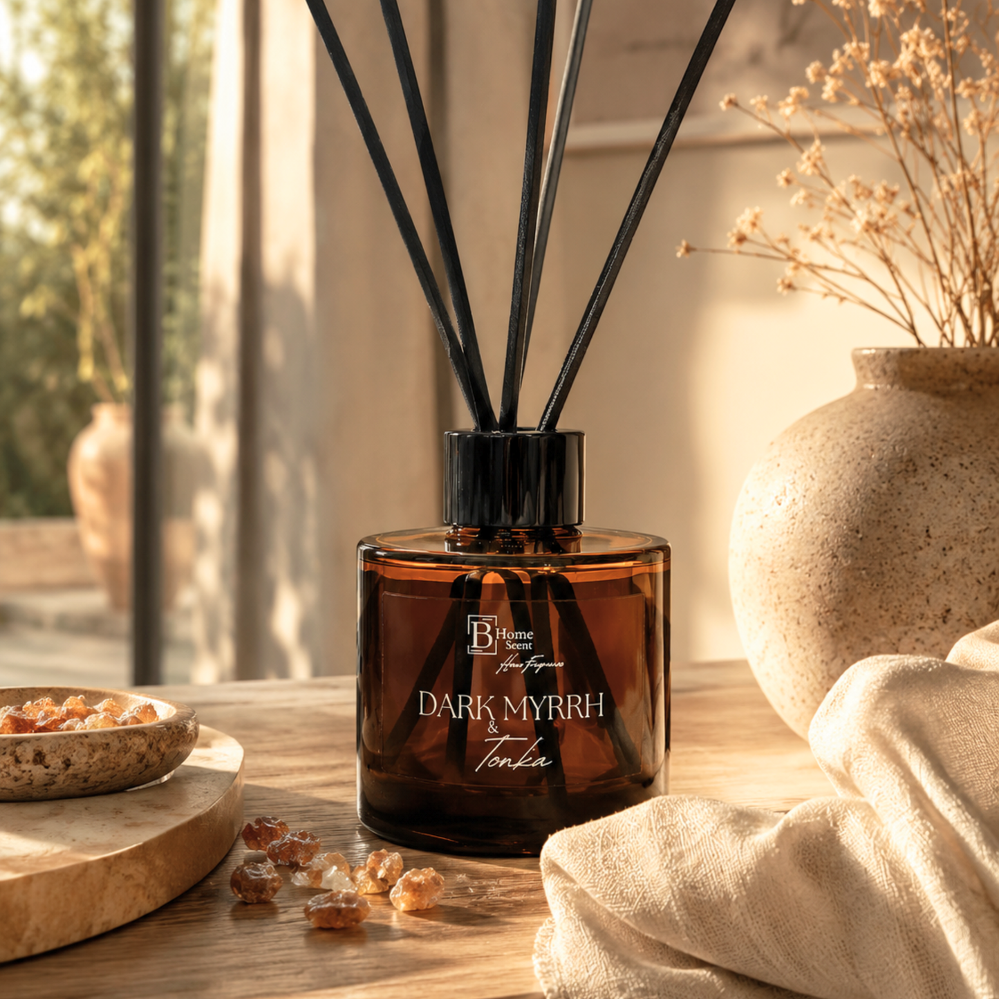 A bottle of 'Dark Myrrh and Tonka' reed diffuser on a wooden surface with decorative elements.