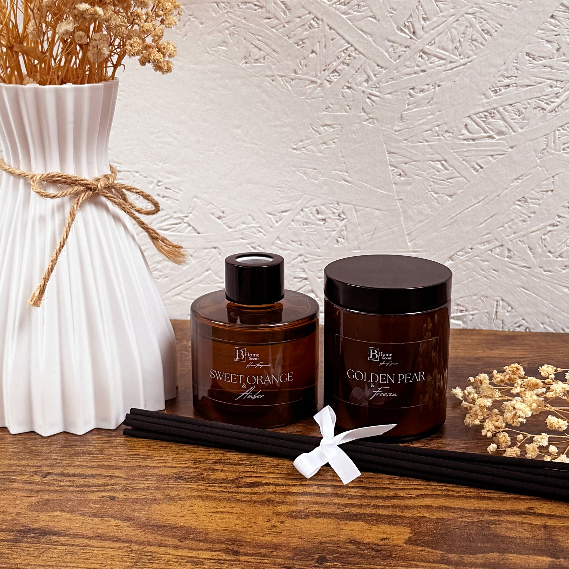 Luxury home fragrance gift set with amber glass candle and reed diffuser styled on wooden table