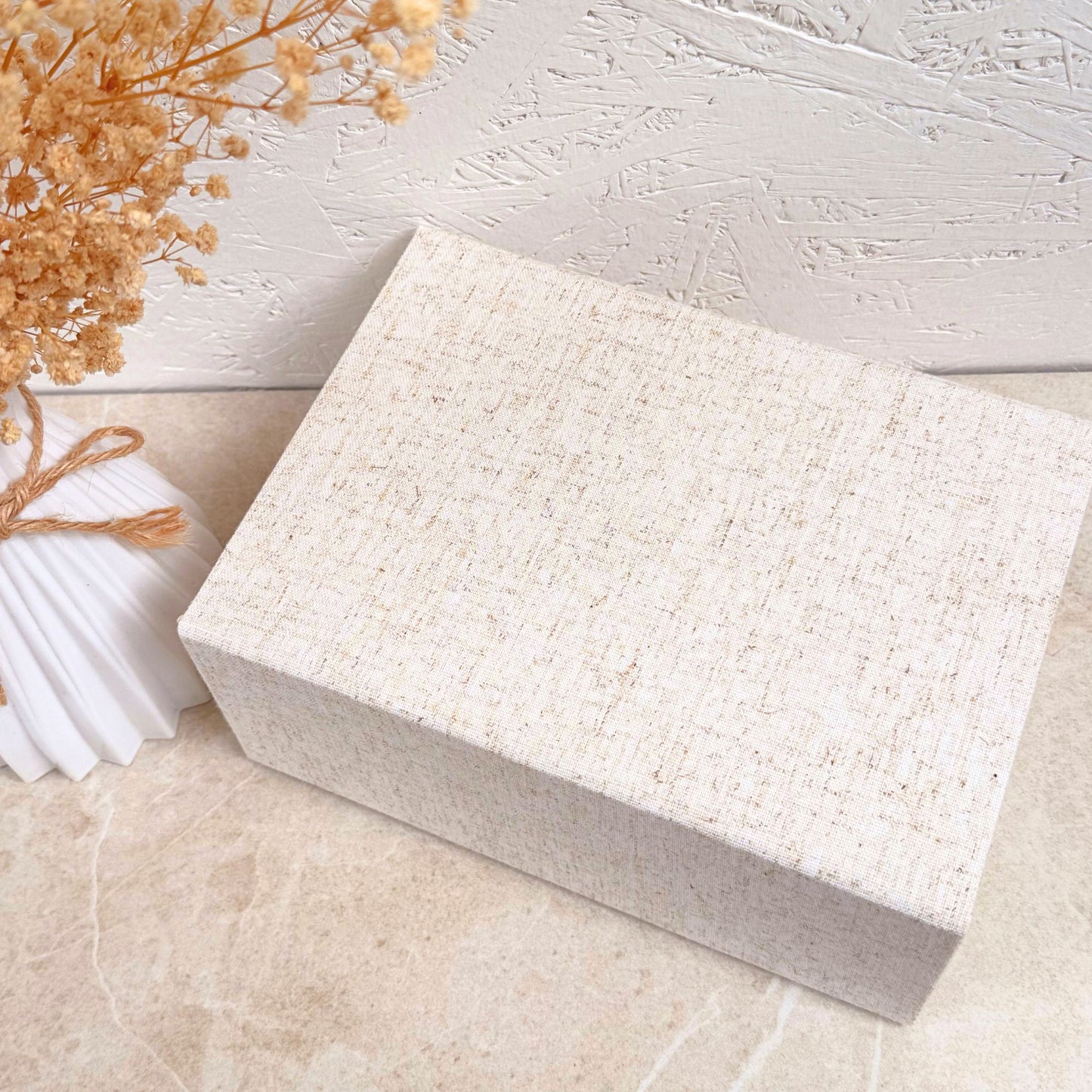 Natural linen gift box on a light   surface with dried flowers.
