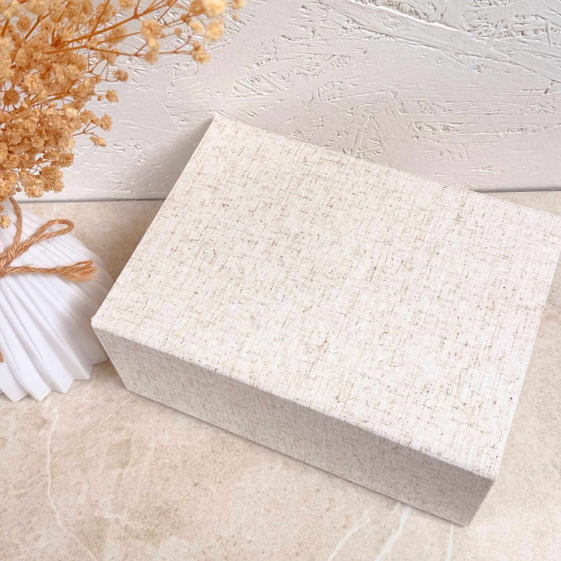 Natural linen gift box on a light   surface with dried flowers.