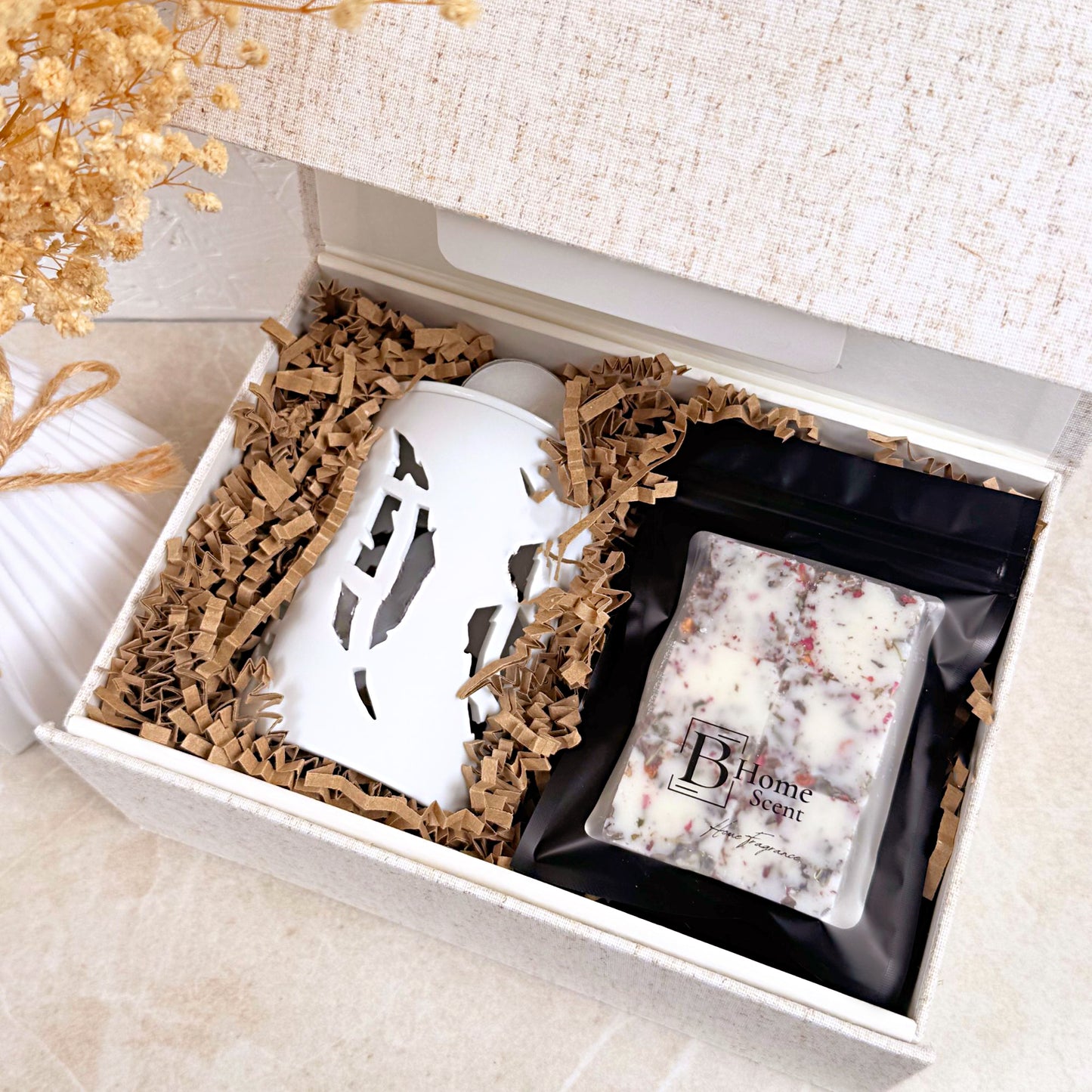 Gift box with a white wax melt burner and a bags of wax melts on a light surface.